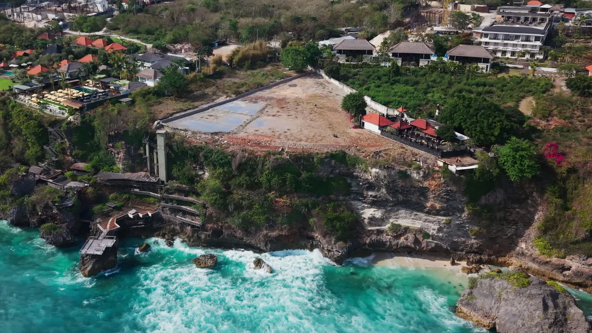 Actual drone view from the ocean, showing the cleared clifftop parcel, neighbouring temple and existing structures at the cliff base.